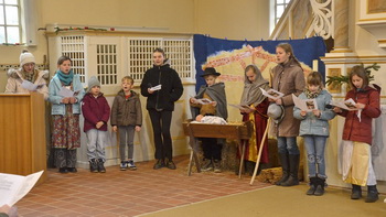 Kinder und Jugendliche stehen bei der Probe f&uuml;r das Krippenspiel um die Krippe herum und singen